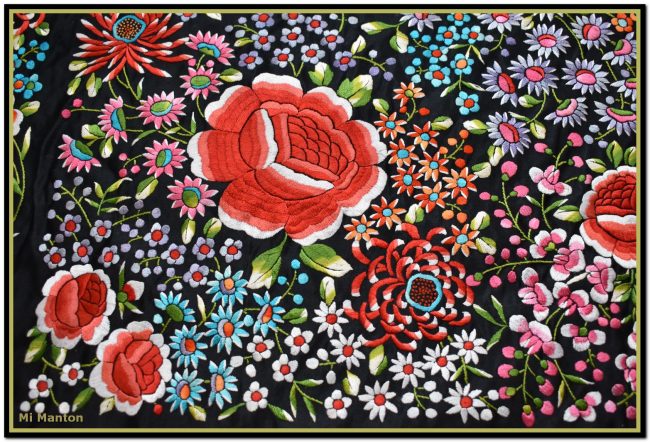 Mantón de Manila de raso negro bordado a mano con muchos motivos florales de espectacular colorido