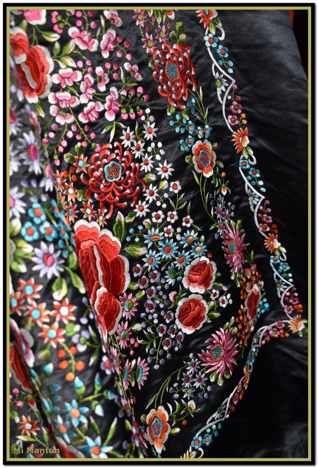Mantón de Manila de raso negro bordado a mano con muchos motivos florales de espectacular colorido